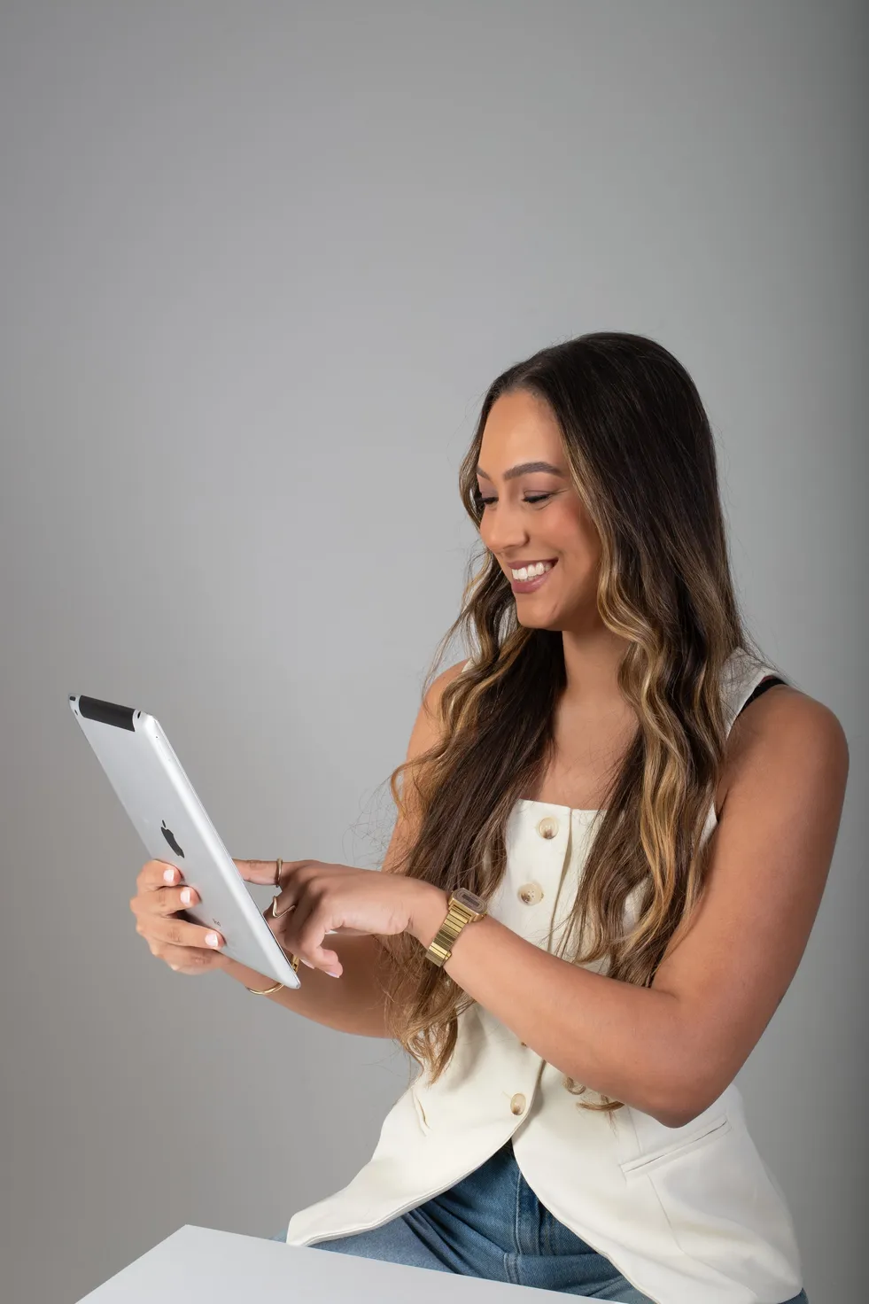 Mulher sorrindo enquanto usa um tablet, em pé.