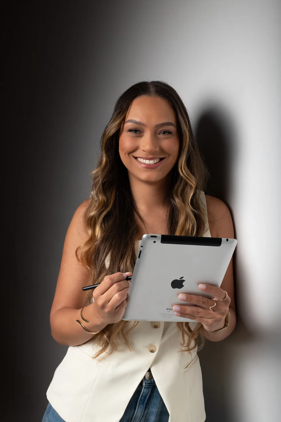 Mulher sorrindo, segurando um tablet e uma caneta digital.