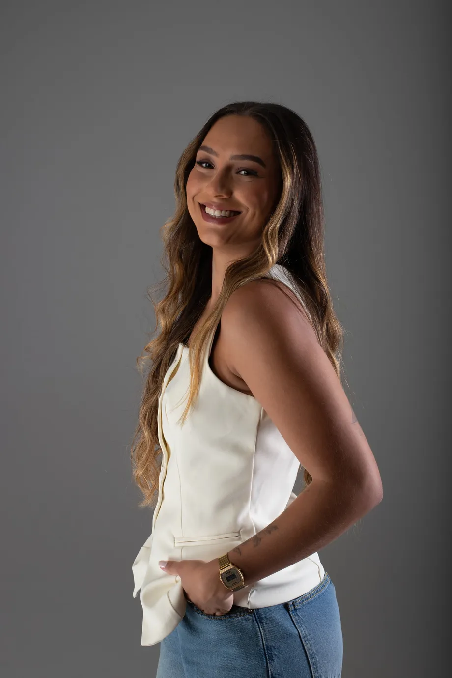 Amanda, fundadora do Clube do Fluente, sorrindo de perfil em estúdio de fundo cinza.